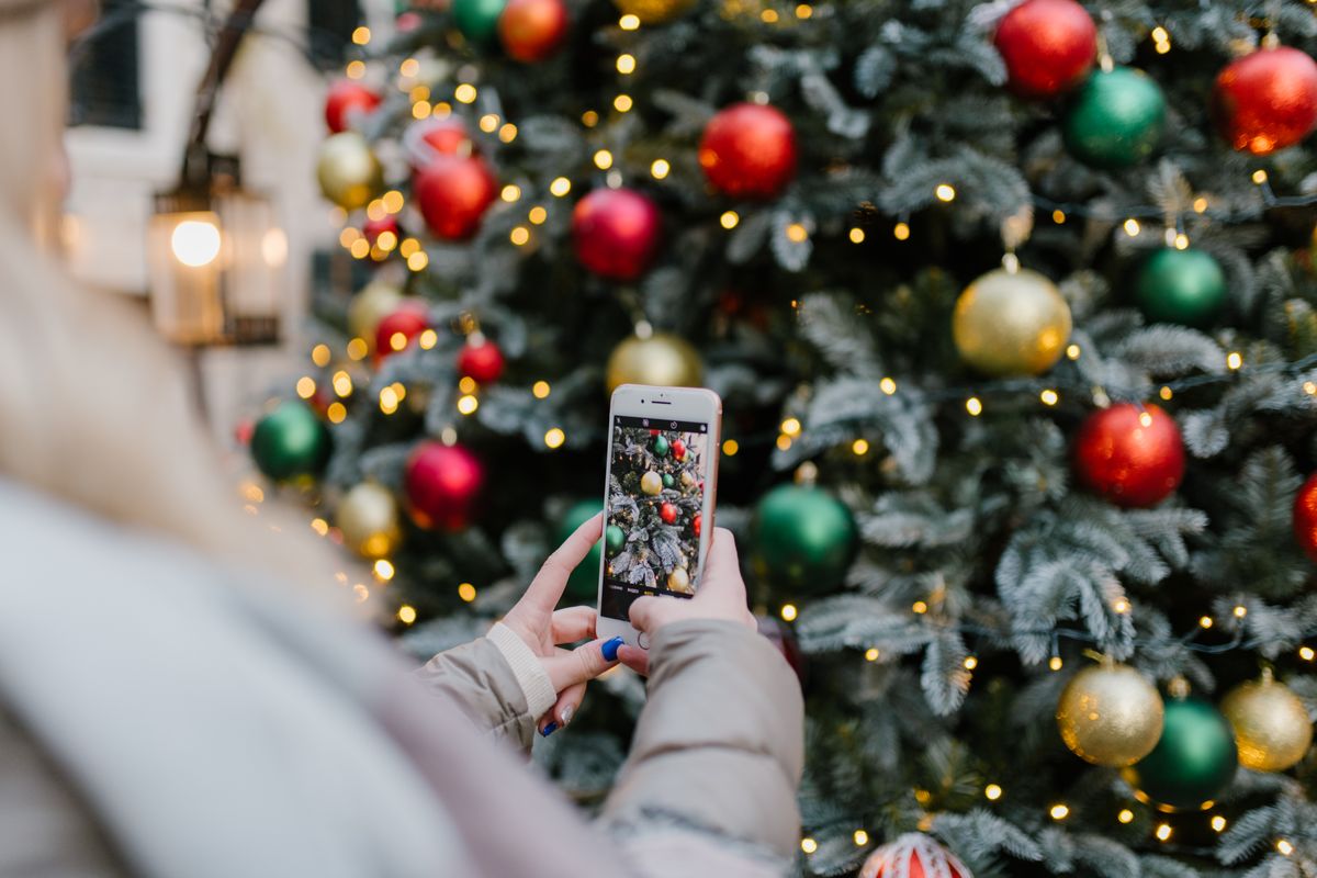 Une personne photographie un sapin de Noël décoré avec son smartphone
